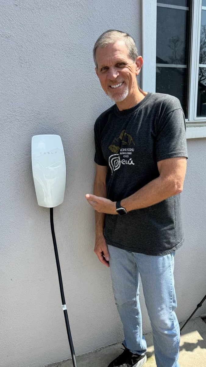 Steve playing Vanna White pointing at the repaired Tesla wall charger.